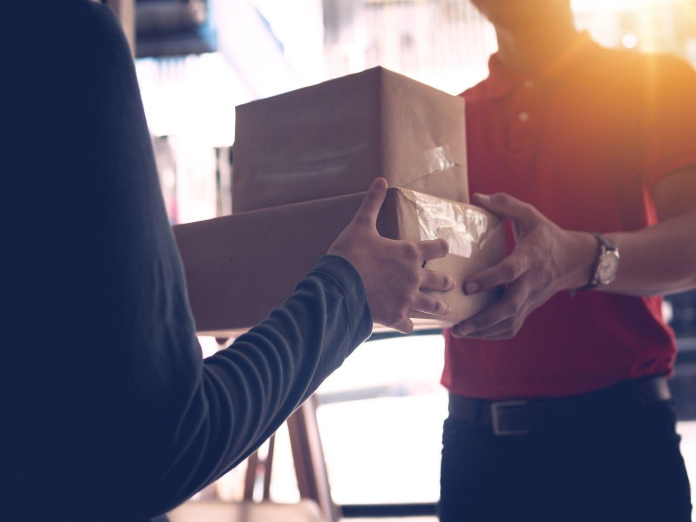A courier handing a sealed parcel to a customer.